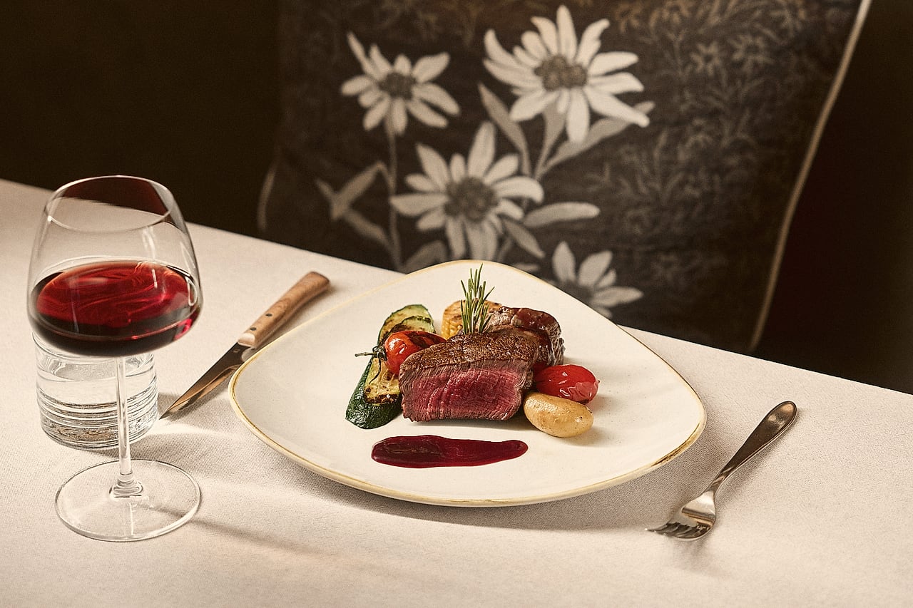 Grilled fillet with vegetables and a glass of red on a white tablecloth