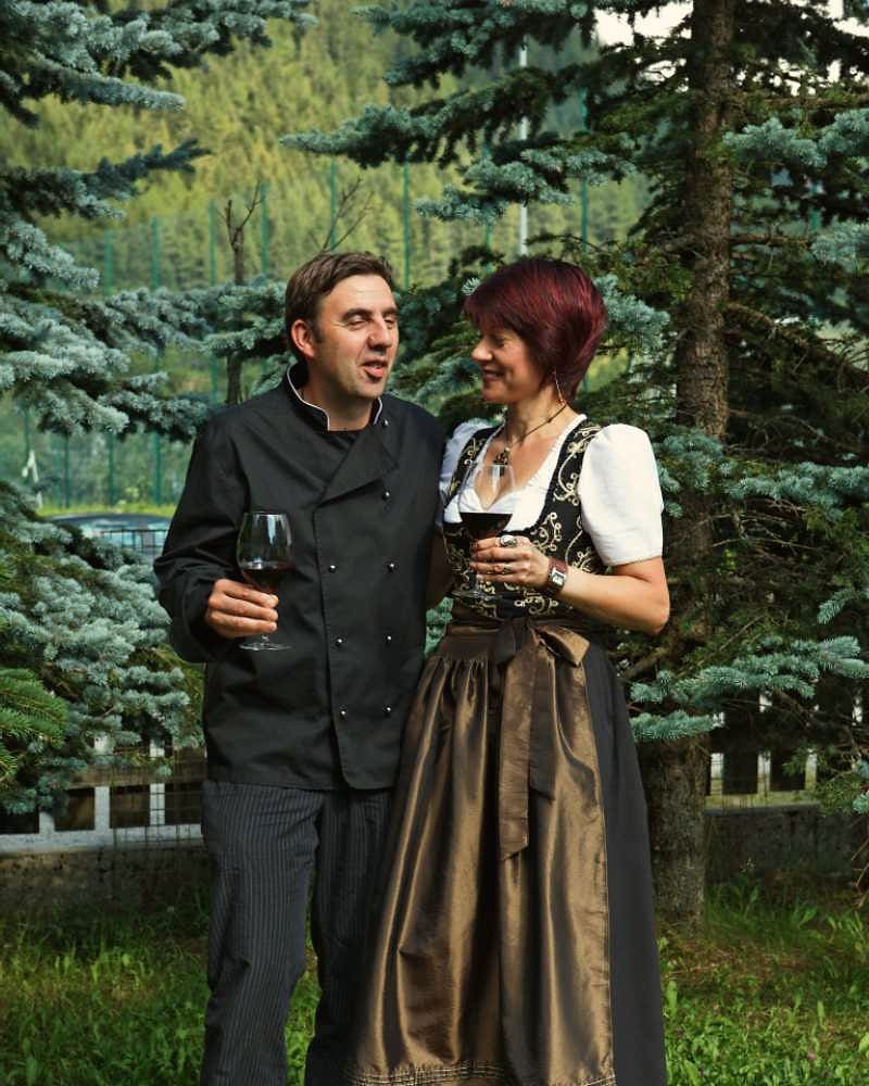 The Adlerkeller hosts with a glass of wine among the spruce trees
